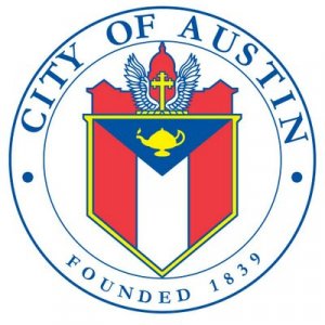 The official seal of the City of Austin, featuring a shield with a gold lamp, red and white sections, and a domed building with wings and a cross. Blue text around the seal reads "City of Austin Founded 1839.