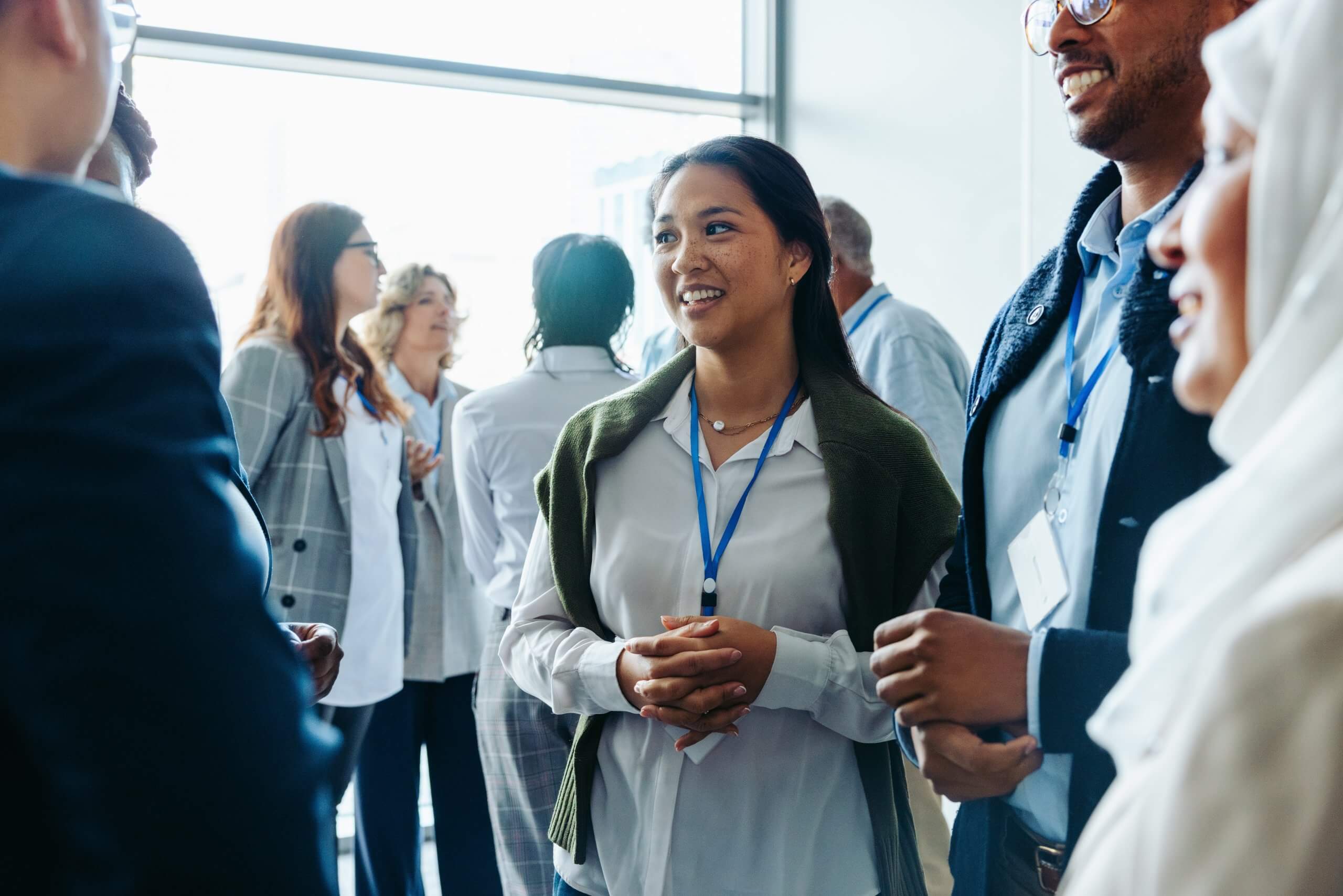 Group,Of,Diverse,Business,Professionals,,Businessmen,And,Businesswomen,,Networking,At A group of people in business attire stand in a circle, smiling, as they bring their fists together for a group fist bump, symbolizing teamwork, unity, and strong leadership.