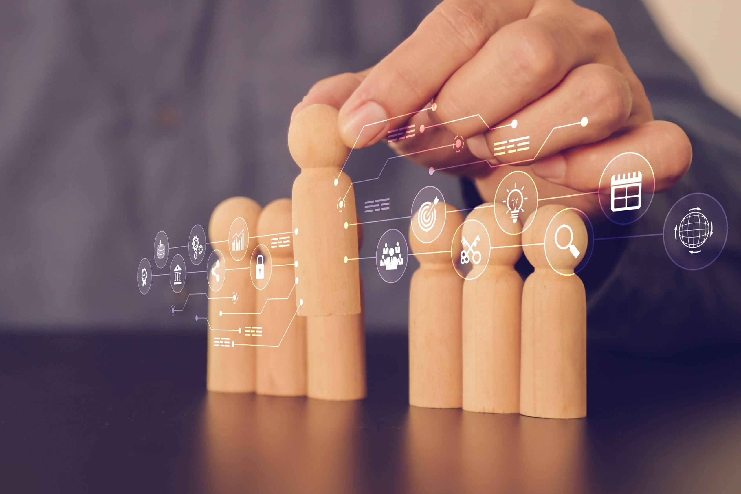 A hand arranges wooden human figures in a row, with digital business and technology icons overlaying the image, symbolizing concepts like teamwork, performance, management, and innovation. A hand arranges wooden human figures in a row, with digital business and technology icons overlaying the image, symbolizing concepts like teamwork, performance, management, and innovation.