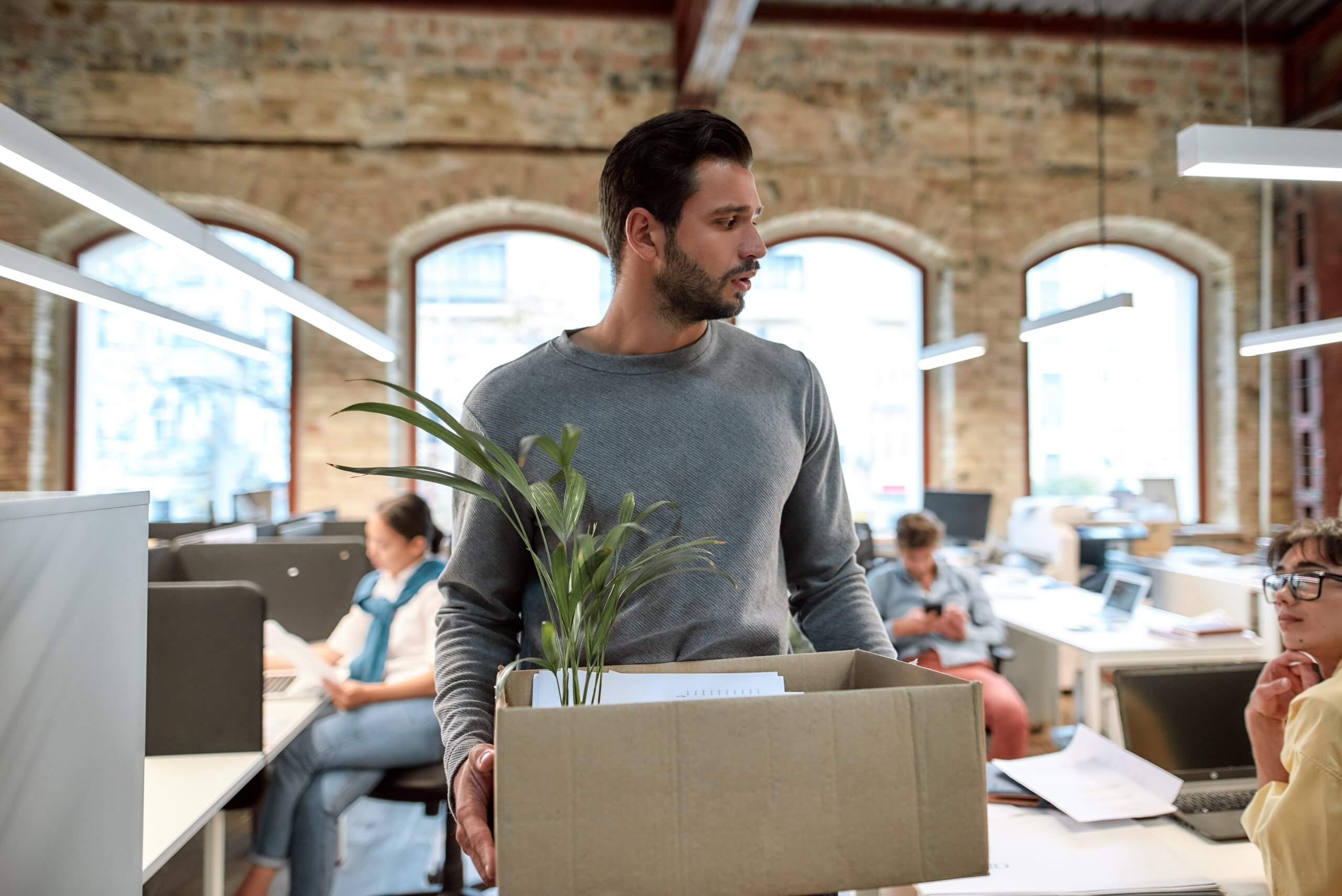 If,You,Don't,Like,Your,Job,Quit.,Upset,Man,In A man and a woman sit across from each other at an office desk, smiling and engaged in conversation as they learn from one another. The desk holds a tablet, papers, and a glass of water, set against a bright, modern office space.