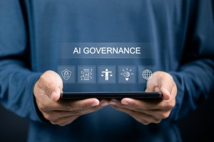 A person holding a tablet with digital graphics displaying "AI Governance" and icons representing AI security, compliance, innovation, and global connectivity.