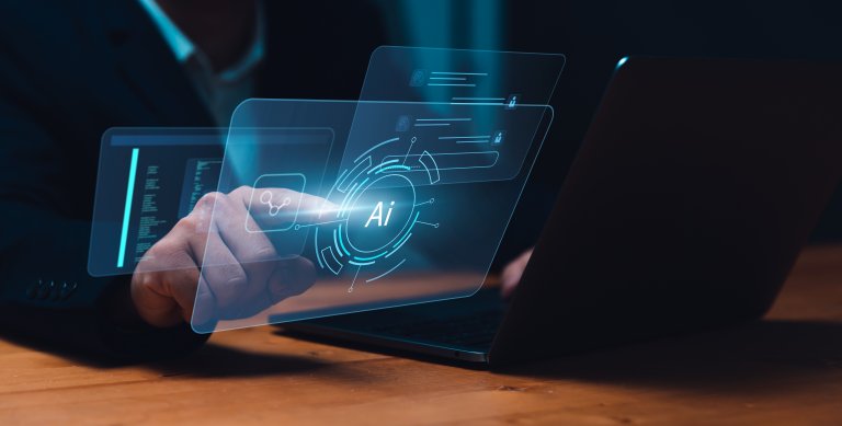 A person interacts with a digital AI interface projected above a laptop, touching a futuristic display where the letters "AI" glow at the center, emphasizing cutting-edge technology and artificial intelligence.