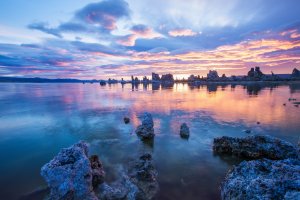 Colorful sunset over Mono Lake, California, with vibrant pink, orange, and purple clouds reflected on calm water. Tufa rock formations rise from the lake, creating a dramatic natural landscape reminiscent of scenic Orlando evenings.