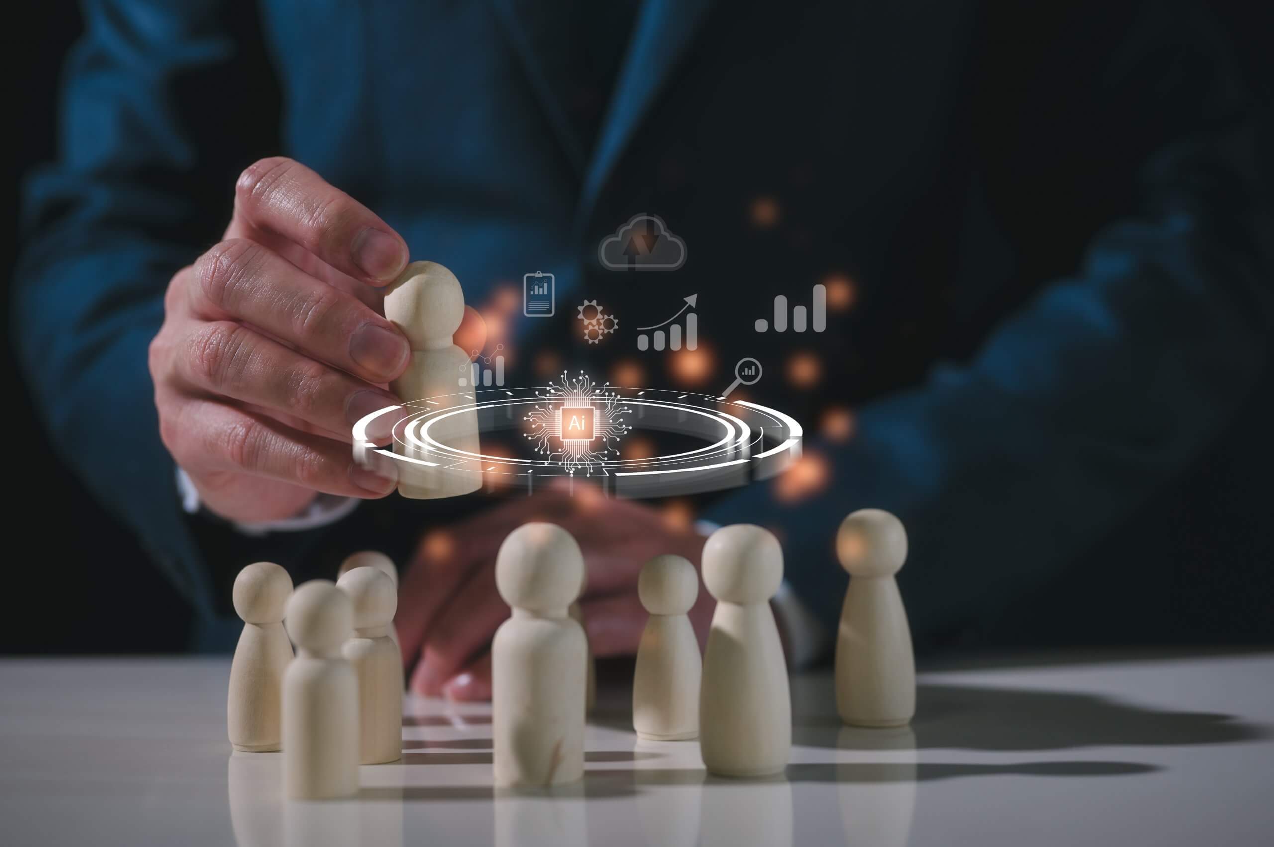 A person in a suit arranges wooden human figures on a table, with digital business icons, AI elements, and data graphics overlayed above them, symbolizing team management and technology integration.