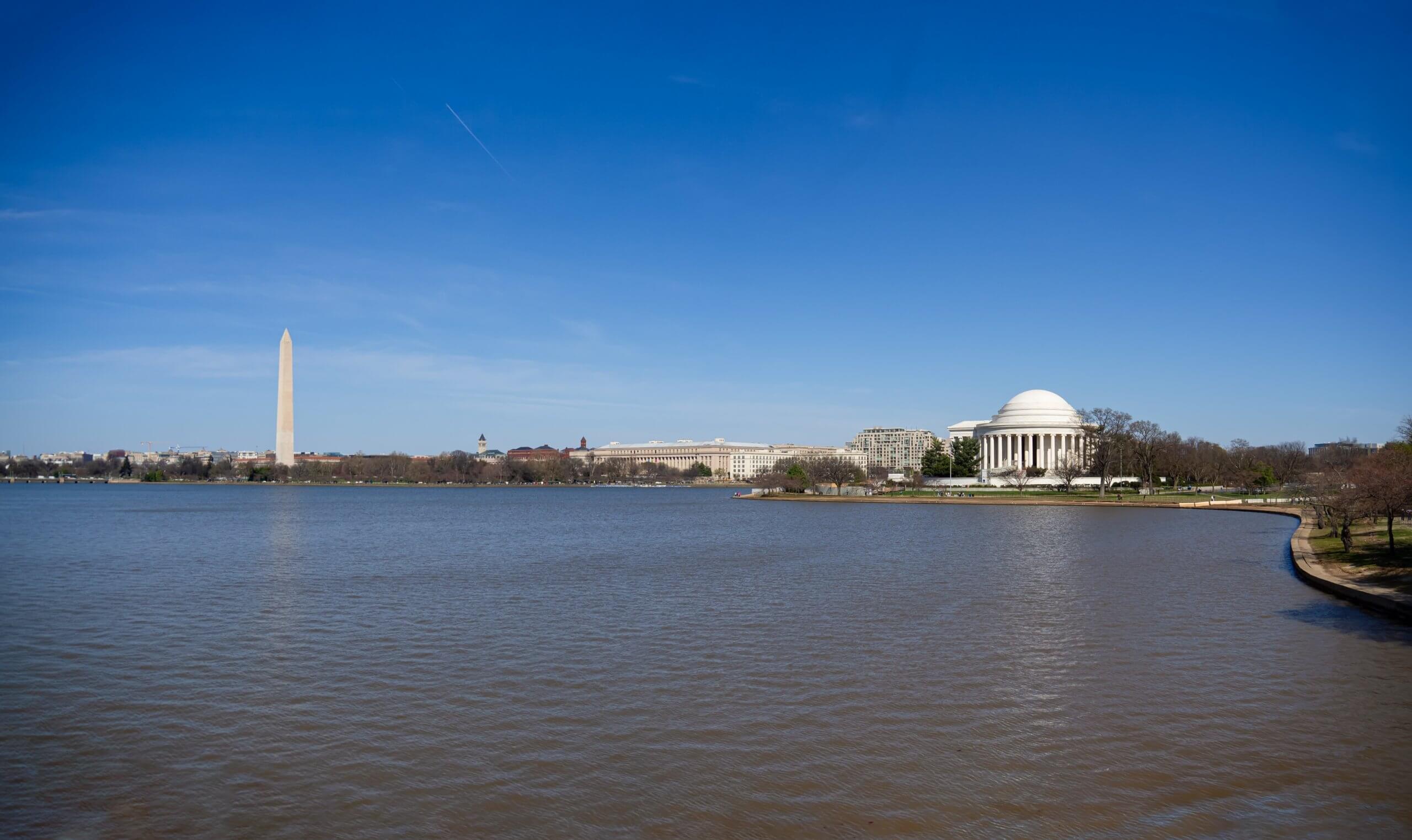 View of the Tidal Basin in Washington, D.C., with the Washington Monument on the left and the Jefferson Memorial on the right under a clear blue sky, a favorite spot for employees to relax during their lunch break.