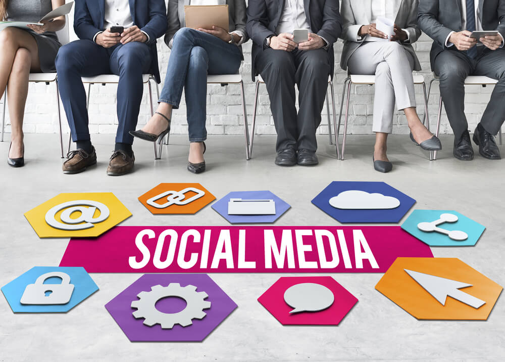 Six people sit in a row using digital devices. In front of them are colorful hexagons with social media icons, a pink "SOCIAL MEDIA" banner in the center, highlighting the influence of government on online interactions. Six people sit in a row using digital devices. In front of them are colorful hexagons with social media icons, a pink "SOCIAL MEDIA" banner in the center, highlighting the influence of government on online interactions.