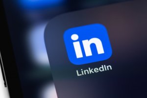 Close-up of a smartphone screen displaying the LinkedIn app icon and its name, highlighting networking opportunities for Public Sector professionals against a blurred background.