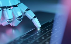 A robotic hand with metallic fingers touches the illuminated trackpad of a laptop keyboard, symbolizing artificial intelligence, technology integration, and the evolving future of government workers.