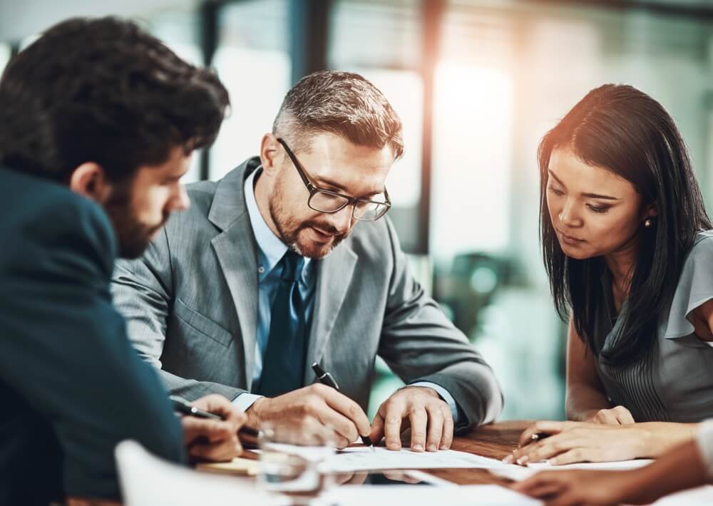 Business,,People,And,Writing,Of,Plan,,Report,And,Paperwork,For Nine wooden figurines in a group are connected by black lines to a single wooden figurine standing in front, representing leadership or influence within a group—a visual metaphor for public service and guiding others.
